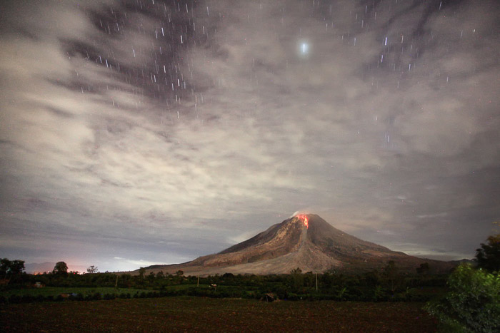 A nighttime picture of a volcano with its lava flow